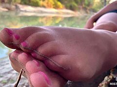 My cute feet in nude tights gently rub together by the autumn river bank.